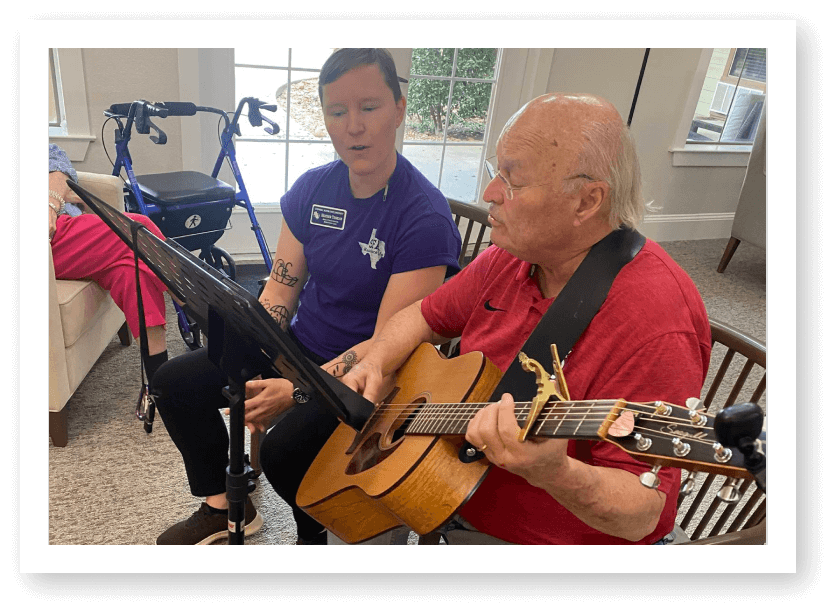 Elderly Man Playing Guitar During Music Therapy Session at Assisted Living Facility