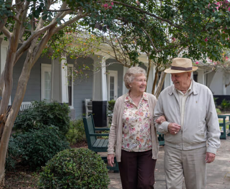 Elderly Couple Walking Together on Outdoor Garden Path at Assisted Living Facility Elderly Couple Walking Together on Outdoor Garden Path at Assisted Living Facility