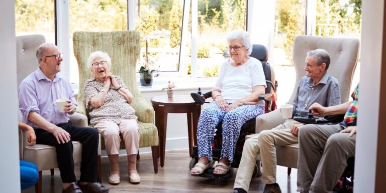 Group of Elderly Residents Socializing in Common Room at Memory Care Facility